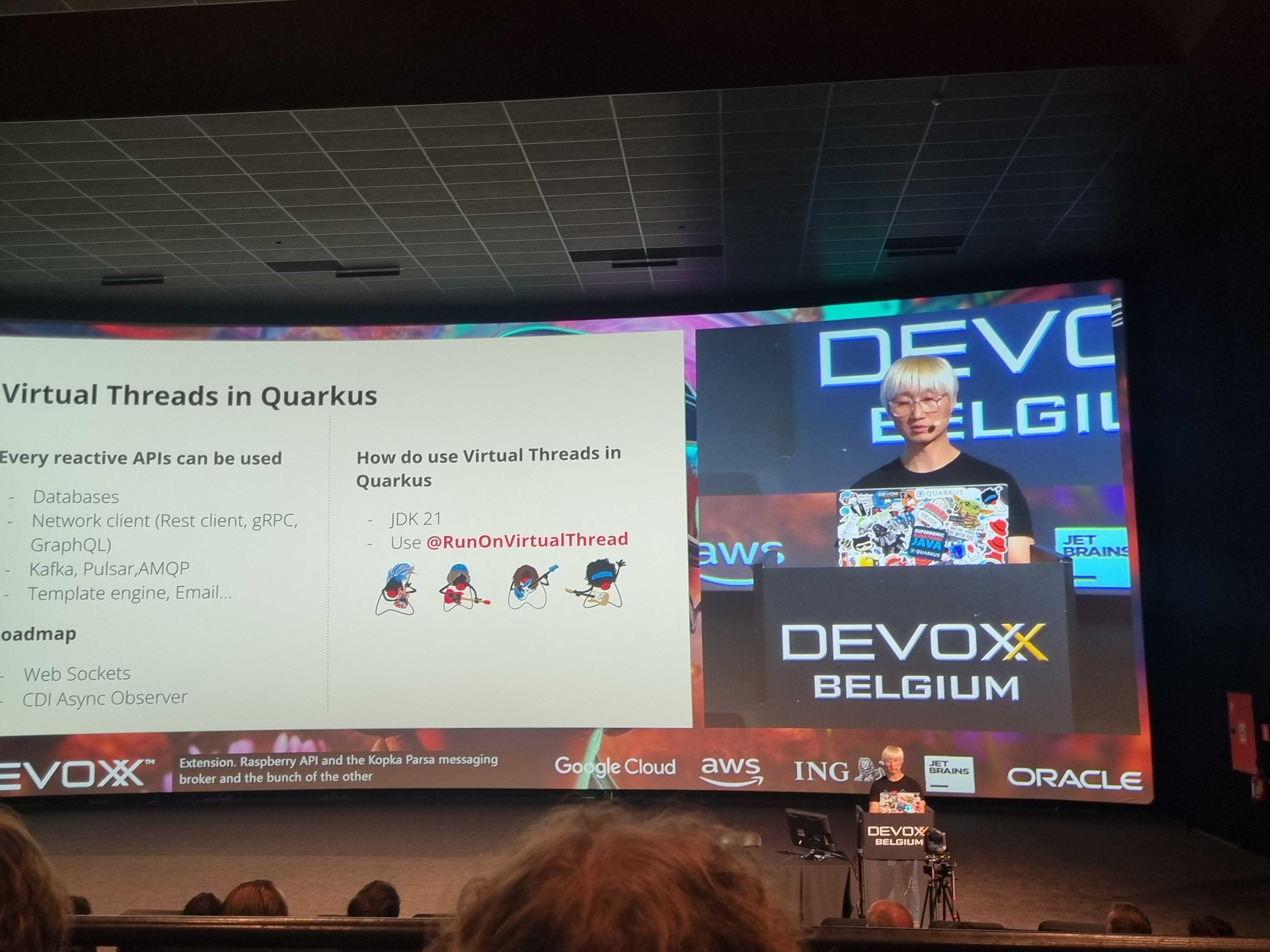 A presenter behind podium with screen titling Virtual Threads in Quarkus.